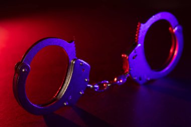 Gece polis baskını ve sen tutuklusun. Kelepçelerin silueti. Flaşlı kırmızı ve mavi polis ışıkları koyu arkaplan.