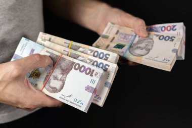 Karanlık arka planda Ukrayna parası tutan adamlar, yakın plan..