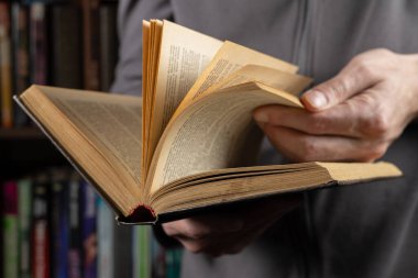 Adam okuyor. Kitap onun elinde. Kapat..