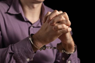 Elleri kelepçeli bir iş adamı mali dolandırıcılıktan tutuklandı, sorgu odasında oturuyor..