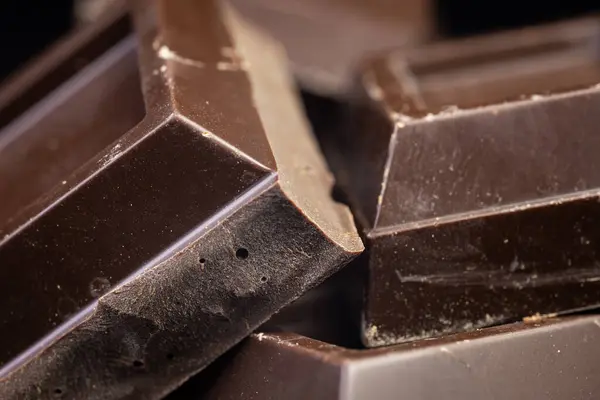 Broken chocolate. Chocolate pieces. Chocolate pieces on dark background