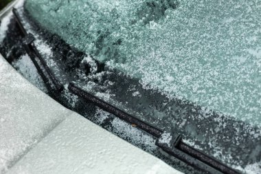 Donmuş arabanın ön camında silecek bıçağı ve kaputu var. Sonbahar sabahı dondurması.