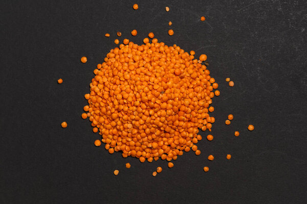 Красная чечевица. Сухие оранжевые чечевица зерна, куча даль, дхал, мазур, линзы culinaris или линзы esculenta на темном фоне.
