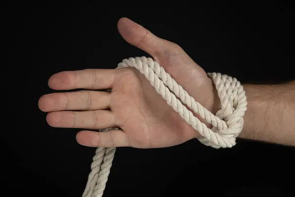 Man\'s hand tied with a rope, vintage effect photo with noise. Pulling man out of a bad situation. Help person conceptual shot. Shackle and restriction.