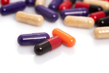 Renkli haplar ya da kapsül bembeyaz bir masaya serilmiş..