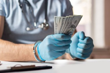 Dolar banknotları ve kelepçeleri olan bir doktor. Tıbbi yolsuzluk, rüşvet, suç kavramı.
