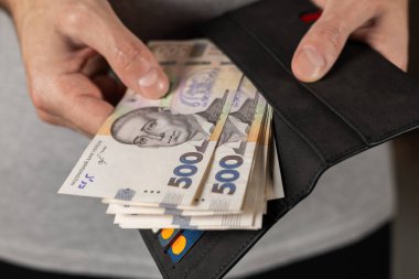 500 hryvniadan oluşan banknot erkek elinde. Üzerinde Ukrayna parası ve kredi kartları olan gri cüzdan..