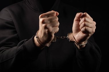 Sandalyede kelepçeli bir adam var. Elleri kelepçeli adamlar suçtan tutuklandı. Elleri arkada, çocuk cezaevi şiddet konseptinde prangalı..