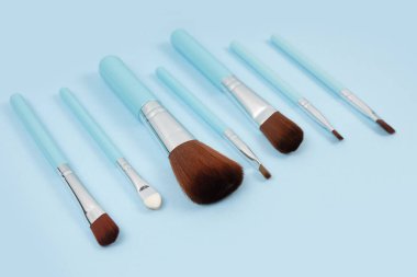 Mavi arka planda kozmetik makyaj fırçası. Makyaj için kozmetik ürün. Yaratıcı ve güzel moda konsepti. Moda. Makyaj fırçası koleksiyonu, üst görünüm, afiş.