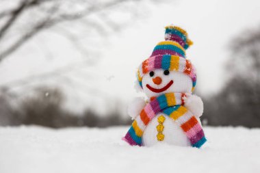 Kış ormanında şapkalı, eşarplı kumaş bir kardan adam. Kış, kar ve çocukluk kavramı