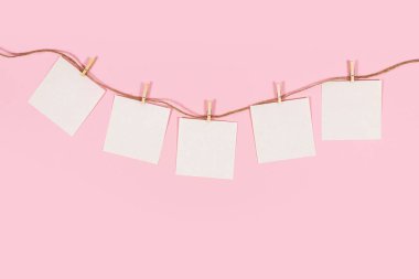 Notlarınızın hatırlaması için boş beyaz kağıdın üst görüntüsü ahşap bir iğneyle pembe arka plana iğnelenmiş..