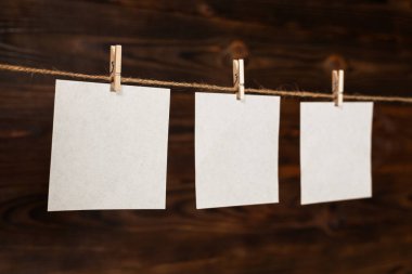Tahta raptiyeyle asılı 3 kağıt kart ya da tahta zemin üzerinde ip iplik iğnesi..