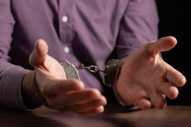 İş adamı yolsuzluktan tutuklandı. Elleri kelepçeli takım elbiseli bir adam.