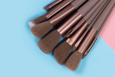 Kozmetik ve güzellik. Mavi arkaplanda makyaj fırçaları ayarlandı.