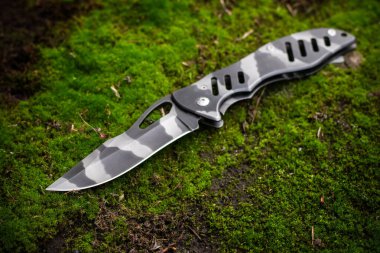 Yosun arka planında hayatta kalmak için taktik katlama bıçağı..