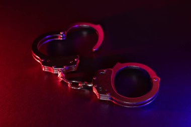 Gece polis baskını ve sen tutuklusun. Kelepçelerin silueti. Flaşlı kırmızı ve mavi polis ışıkları koyu arkaplan.