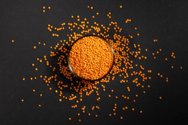 Koyu arkaplanda cam tabakta kırmızı mercimek.