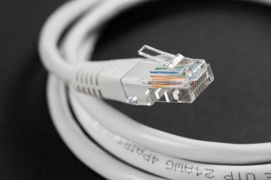 Beyaz bir RJ45 Ethernet kablosunun siyah bir masada yakın plan makro görüntüsü..