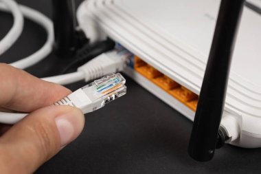 İnternet kablosunu wi-fi yönlendiricisine takan adam.