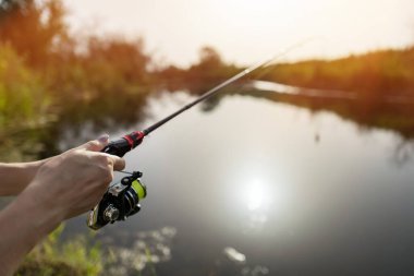 Closeup of a female hands holding a fishing rod and reel. clipart