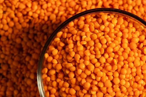 stock image Raw red lentils are scattered out of the glass bowl.