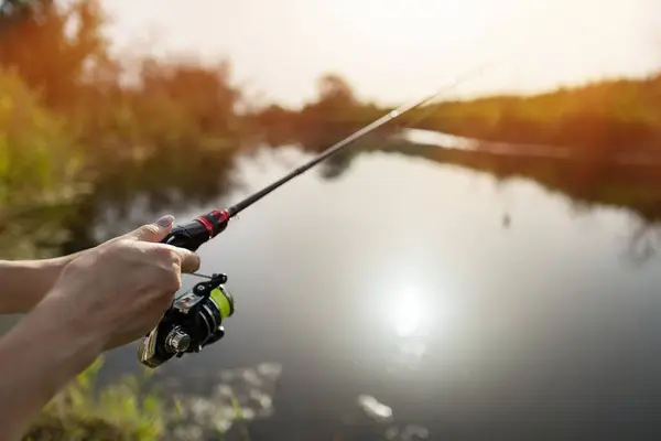 Stock image Closeup of a female hands holding a fishing rod and reel.