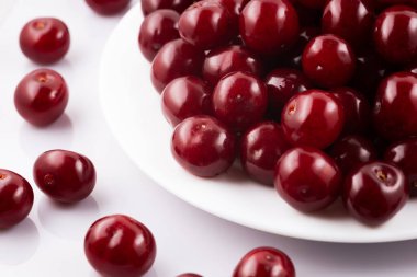 Beyaz arka planda izole edilmiş tabakta olgun kırmızı kirazlar.