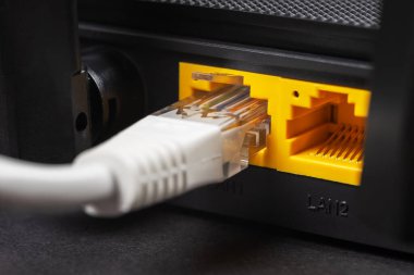 Karanlıkta bir ethernet kablosunu kablosuz yönlendiriciye bağla. Ethernet, rj45 ve elektrik kabloları yönlendiriciye bağlı. Ağ konsepti