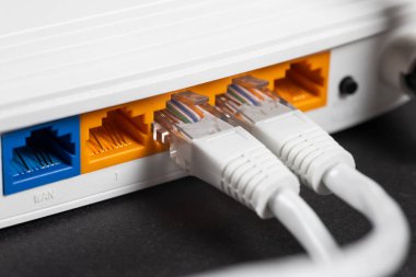 Karanlıkta bir ethernet kablosunu kablosuz yönlendiriciye bağla. Ethernet, rj45 ve elektrik kabloları yönlendiriciye bağlı. Ağ konsepti