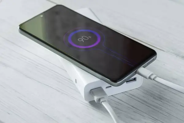 Elektrik faturası ve cep telefonu beyaz ahşap masada..