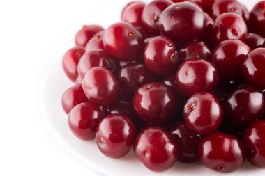 Beyaz arka planda izole edilmiş tabakta olgun kırmızı kirazlar.