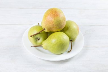 Beyaz masada bir tabakta taze armut meyvesi. Sağlıklı meyve.