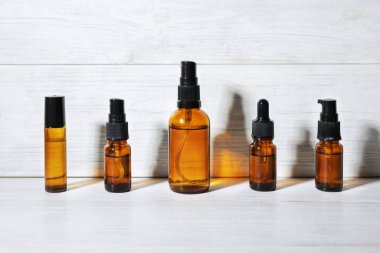 Kozmetik için kehribar cam şişeler, doğal ilaçlar veya beyaz arka planda izole edilmiş gerekli yağlar.