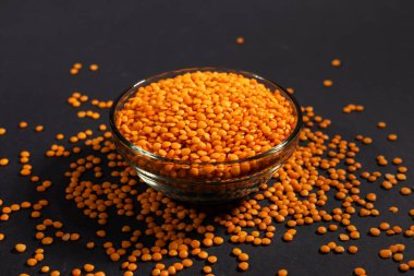 Cam kasede kırmızı mercimek. Kuru turuncu mercimek tanecikleri, dal yığını, çiğ daal, dhal, mazoor, Lens Culinaris veya Lens esculenta koyu arka planda.