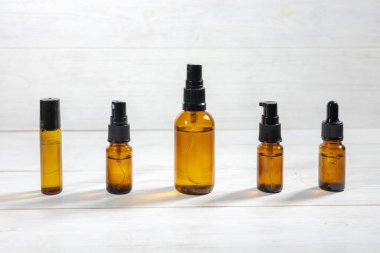 Kehribar şişelerinde yüz sıvısı ve ahşap masa üzerinde keten havlu var..