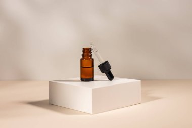 Kehribar cam kozmetik şişeleri krem ya da sıvı ile bej arka planda beyaz beton podyumda cilt bakımı için. Doğal cilt bakımı kavramı