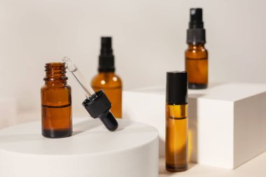 Geometrik kaide podyumunda kehribar kozmetik şişesi, bitkilerin doğal gölgelerini içeren ürün ambalajı, peptitli yaşlanma önleyici serum, kozmetik modelleme, biyofilik konsept..