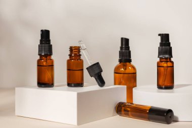 Bej arka planda podyumda kehribar cam damlatıcı şişesine masaj yap. Doğal SPA güzellik ürünü tasarımı.