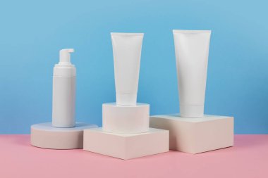 Podyumda etiketsiz beyaz plastik tüpler. Kozmetik ürünleri reklamı sahnesi.