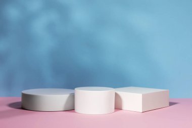 Soyut gerçeküstü sahne. Mavi arka planda bitki gölgeli beyaz podyumları olan boş sahne. Kozmetik ürün ambalaj modelleme sunumu için kaldırım taşı