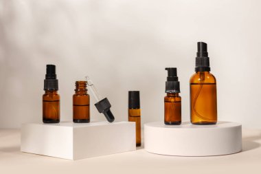 Bej arka planda bir podyumda pipeti olan kahverengi cam şişe, doğal kozmetik konsept..