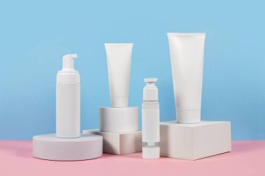Reklamlar için güzel kozmetik şablonlar, plastik krem tüpleri ve podyumlu mavi arka planda şişeler. Premium ürün için güzellik tasarımı