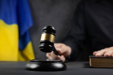 Justice and court concept in Ukraine. Judge hold gavel and law book on a flag background. clipart