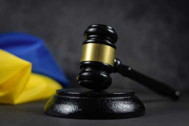 Karanlık arka planda Yargıç Tokmak ve Ukrayna bayrağı. Mavi Ukrayna bayrağı ve ahşap yargıç tokmağı. Ukrayna mahkemesi, hukuk, otorite kavramı. Ukrayna 'da çatışma ve savaş.