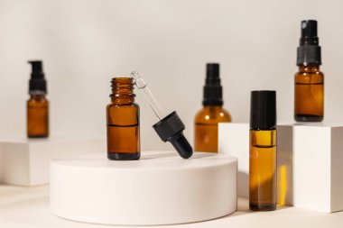 Beyaz podyumda pipetli Amber kozmetik şişesi, ürün ambalajı, peptitli yaşlanma önleyici serum, kozmetik modelleme, spa konsepti.