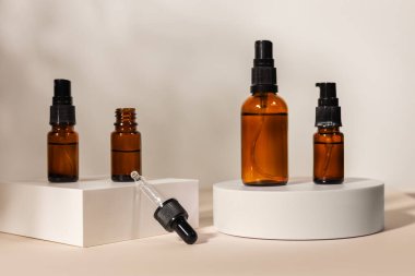 Bej arka planda podyumda kehribar cam damlatıcı şişesine masaj yap. Doğal SPA güzellik ürünü tasarımı.
