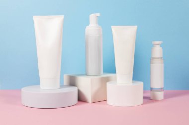 Reklamlar için güzel kozmetik şablonlar, plastik krem tüpleri ve podyumlu mavi arka planda şişeler. Premium ürün için güzellik tasarımı