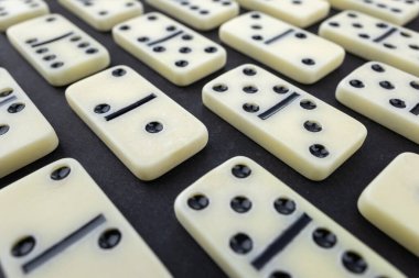 Satranç taşlarının ve dominoların düz kompozisyonu karanlık masanın üzerinde yatıyordu..