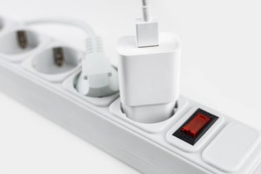 mobile phone chargers connected to electrical power strip. Various devices charging concept,