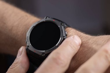 Erkek elleri akıllı saat kullanıyor. İş adamı elinde akıllı bir bant kullanır ve ekrandaki zamanı takip eder..